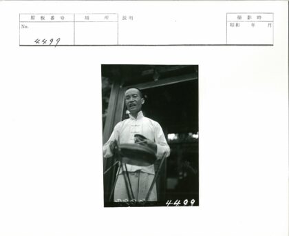 传统服装男子持手鼓建筑前.jpg