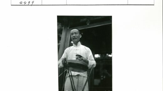 传统服装男子持手鼓建筑前.jpg