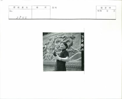 女子持卷站龙雕墙前.jpg
