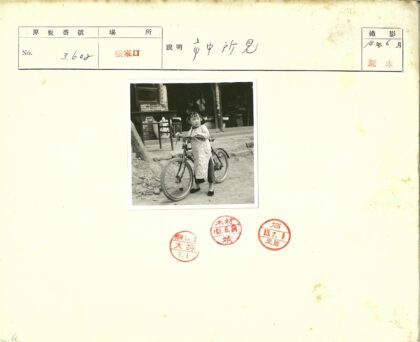 女孩骑自行车在砖墙建筑前.jpg