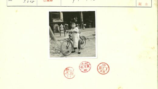 女孩骑自行车在砖墙建筑前.jpg