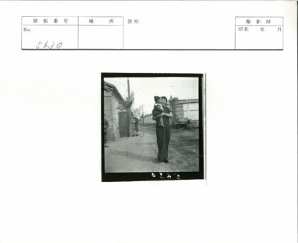 妇女抱孩站砖墙小路.jpg