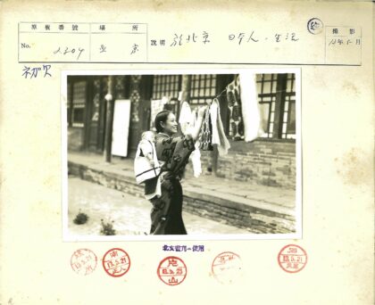 妇女背婴晾衣砖房背景.jpg
