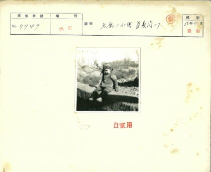 戴帽孩童坐石墙枯树背景.jpg