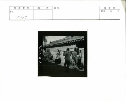 男子扛杆走过黄包车.jpg