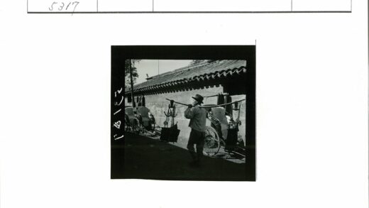 男子扛杆走过黄包车.jpg