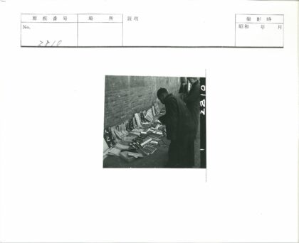 男子检查砖墙旁书籍与书法.jpg