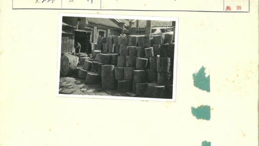 砖房前工人整理原木堆.jpg