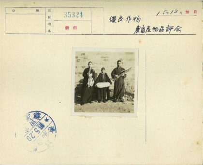 三人持物立于石墙前.jpg