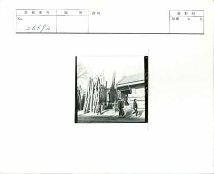 三人走过瓦顶建筑旁木堆.jpg