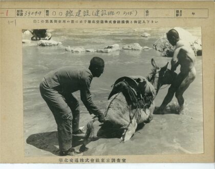 两人牵驴涉水岩石河岸.jpg