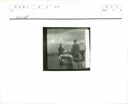 乌云下人群聚集的桌子旁两男子.jpg