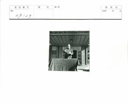 人物站在门廊前持纸.jpg
