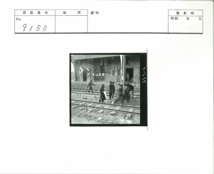 人群聚集铁轨旁砖建筑前旗帜下.jpg