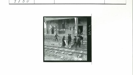 人群聚集铁轨旁砖建筑前旗帜下.jpg
