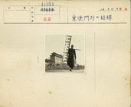 传统建筑前持拨浪鼓的人.jpg