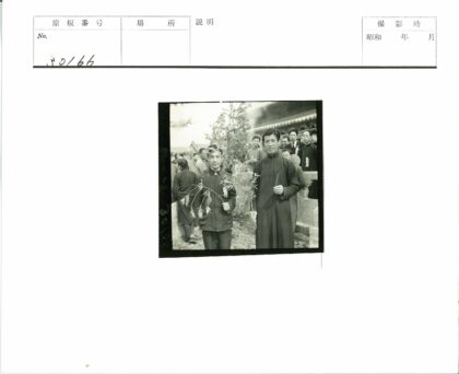 传统建筑前持树枝男子与人群.jpg