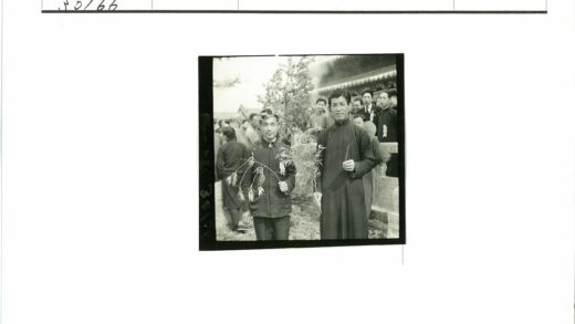传统建筑前持树枝男子与人群.jpg