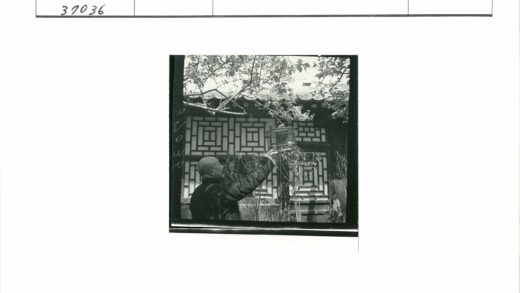 传统建筑前持鸟笼的男子.jpg