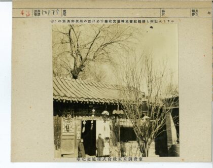 传统建筑前挂饰男子与枯树晴空.jpg