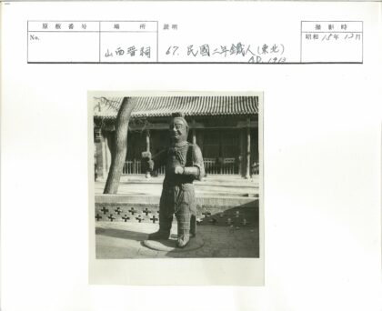 传统建筑前武士雕像与枯树.jpg