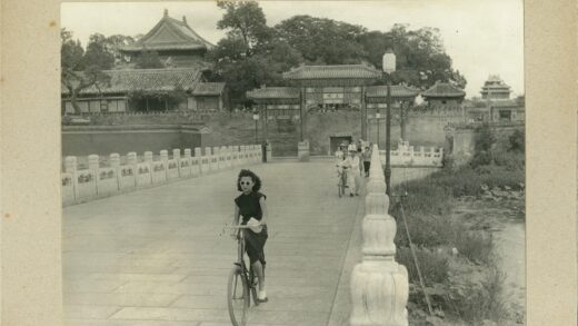 传统建筑前骑自行车的妇女.jpg