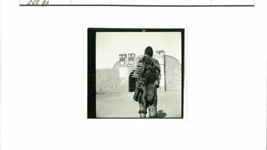 传统服装男子背木板站石砌建筑前.jpg