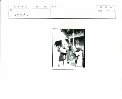传统服饰男子持旗杆建筑前.jpg