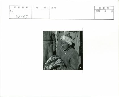 传统毛皮帽男子持图案织物户外合影.jpg
