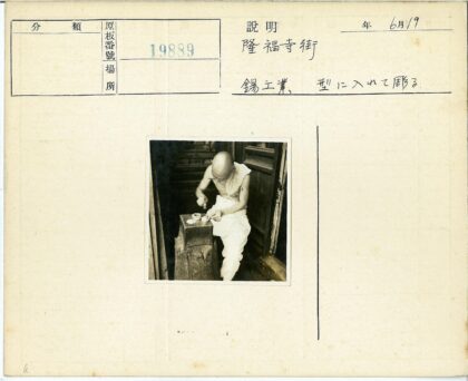 光头男子坐木凳摆弄物件.jpg