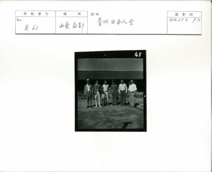 六名男子与孩子的茅草屋前合影.jpg