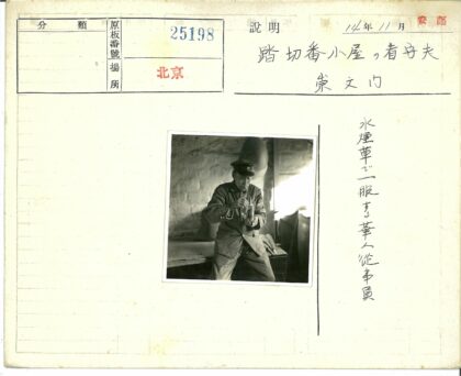制服男子倚木抽烟斗砖墙圆物.jpg