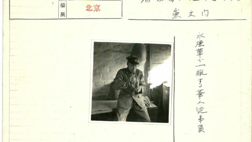 制服男子倚木抽烟斗砖墙圆物.jpg