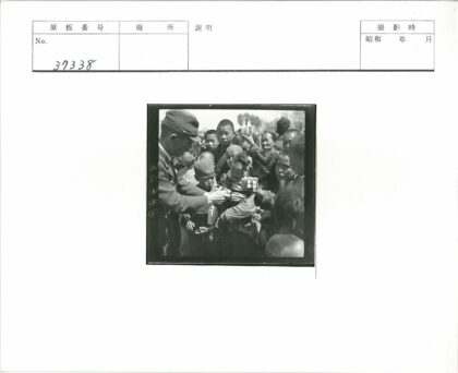 制服男子户外分发物品给孩子们.jpg