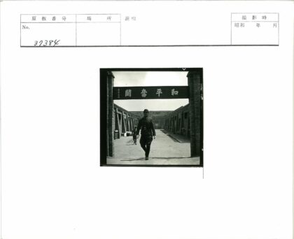 制服男子站砖砌建筑汉字牌下.jpg