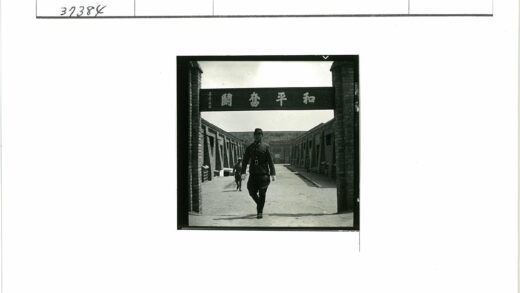 制服男子站砖砌建筑汉字牌下.jpg