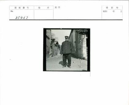 制服男子站立砖墙小巷.jpg