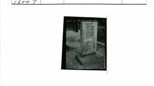 刻字石柱与砖墙树木背景.jpg