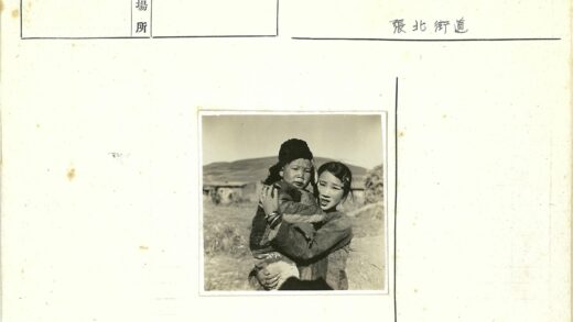 女孩抱孩子在山区小屋前.jpg