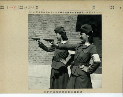 女警持枪站砖墙前.jpg