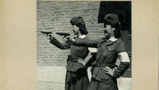 女警持枪站砖墙前.jpg