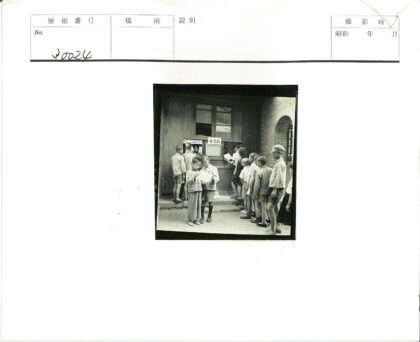 孩子们在砖墙建筑外读报纸.jpg