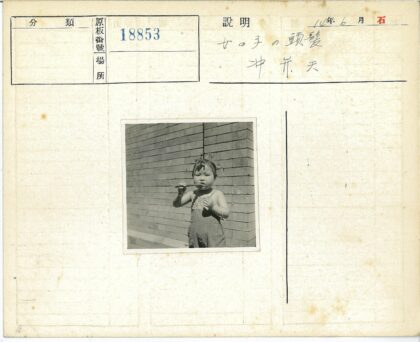 孩子咬棍子站在砖墙前.jpg