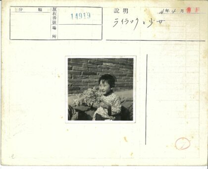 孩子持花站砖墙旁.jpg