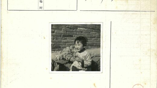 孩子持花站砖墙旁.jpg