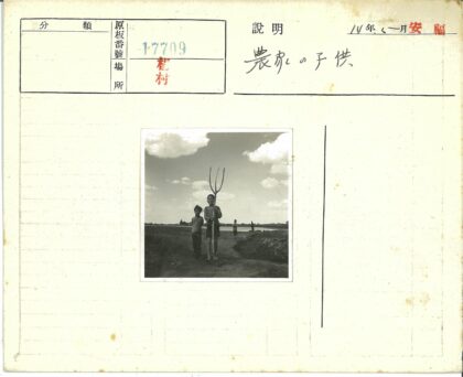 孩童持干草叉行走土路.jpg