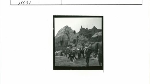 工人搬运大袋子老建筑背景.jpg
