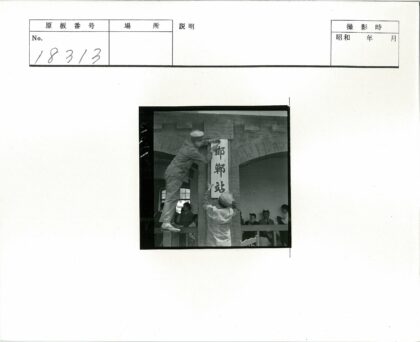 工作人员在建筑前挂汉字牌.jpg