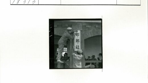 工作人员在建筑前挂汉字牌.jpg