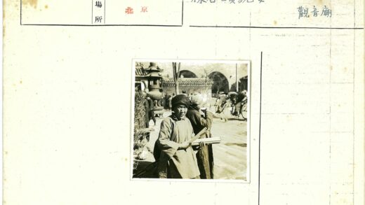 建筑前持圆柱物的老人与人群.jpg